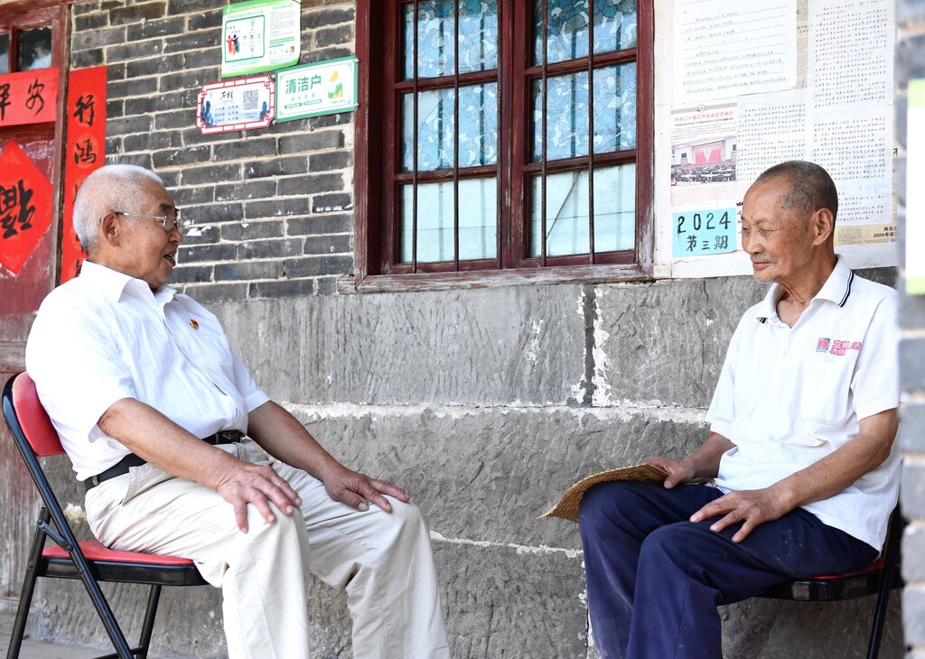 譚長(zhǎng)林（左）與當(dāng)?shù)厝罕姇痴勦l(xiāng)風(fēng)文明建設(shè)