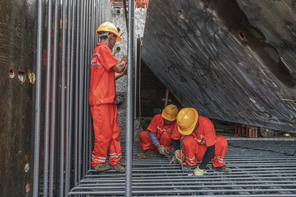 2、钢筋工霍声国（左一）与工友冒着酷暑进行钢筋绑扎作业