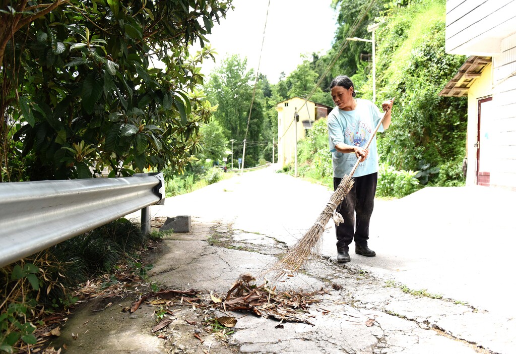 王洪秀在清扫家门口的公路