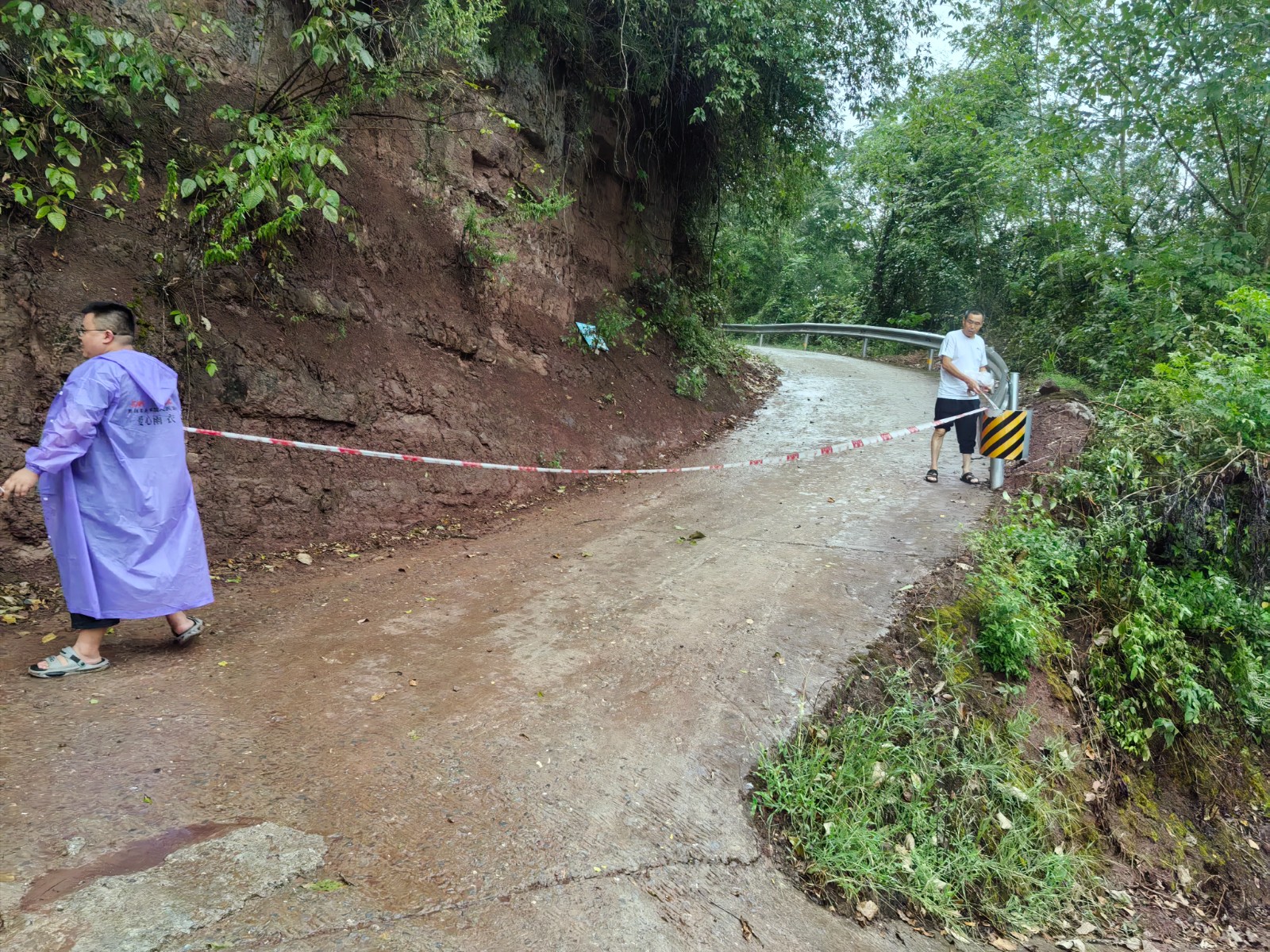 双桂镇石宝村,村干部在生机坡危岩处拉警戒线,对该路段实行断道。拍摄:彭群英.jpg