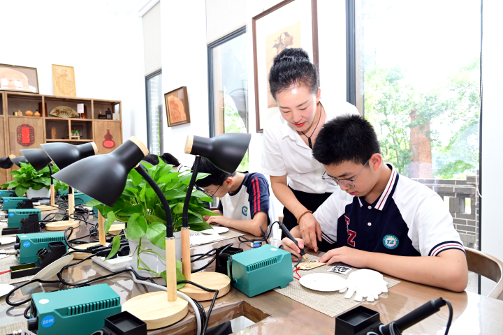 一  高磊在小湾社区的烙画工坊教授孩子们非遗技艺。记者 王茂松摄.jpg