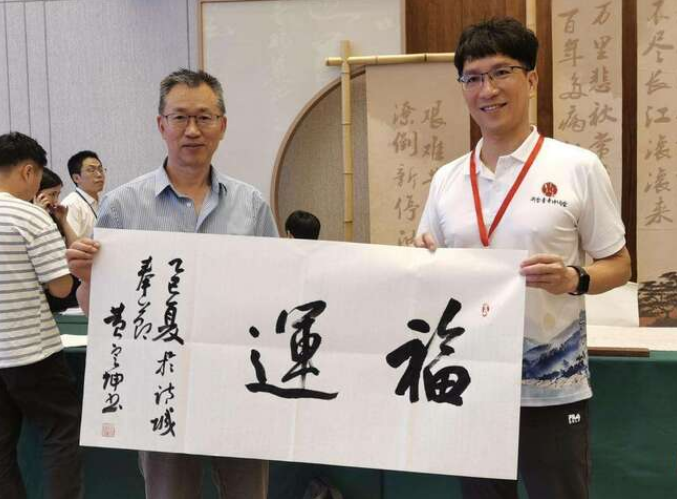 黄定坤（左）与青年交流书法艺术。（受访者供图）